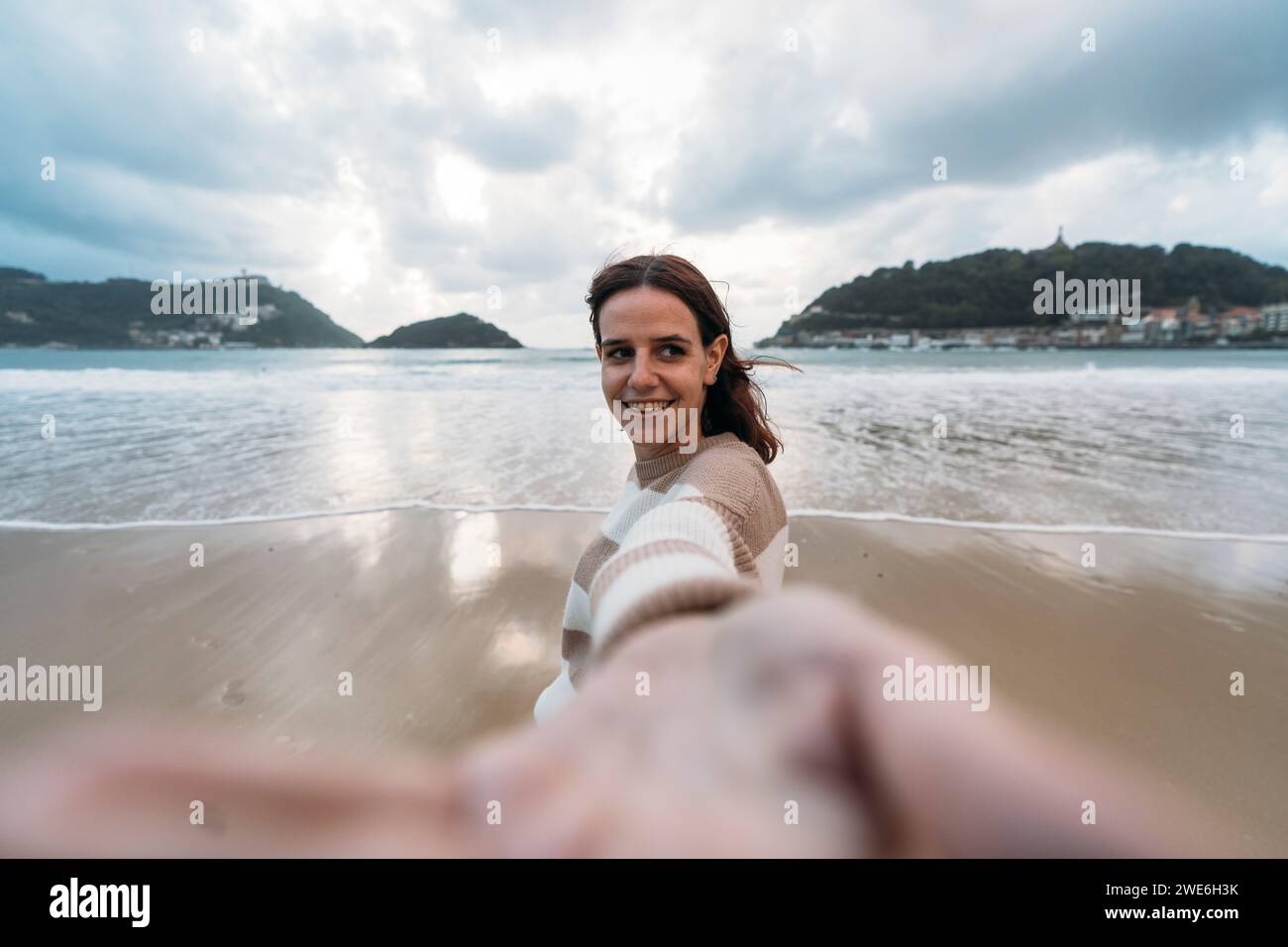 Young woman at Playa de la Concha shore under cloudy sky Stock Photo