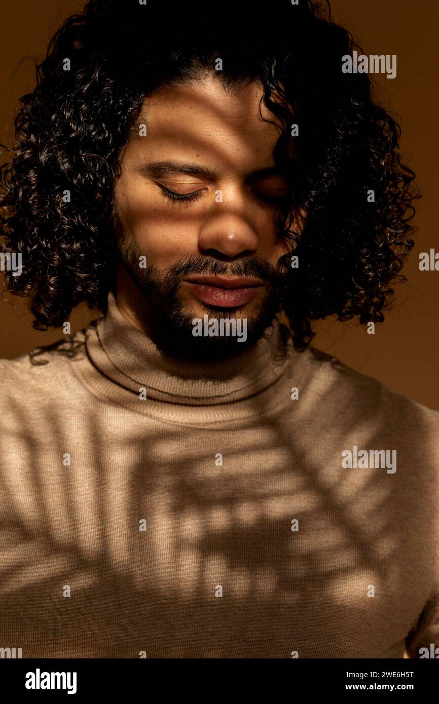 Man with curly hair and eyes closed under shade Stock Photo