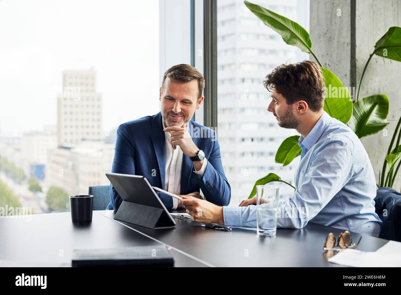 Smiling businessmen having discussion over tablet PC at office Stock Photo