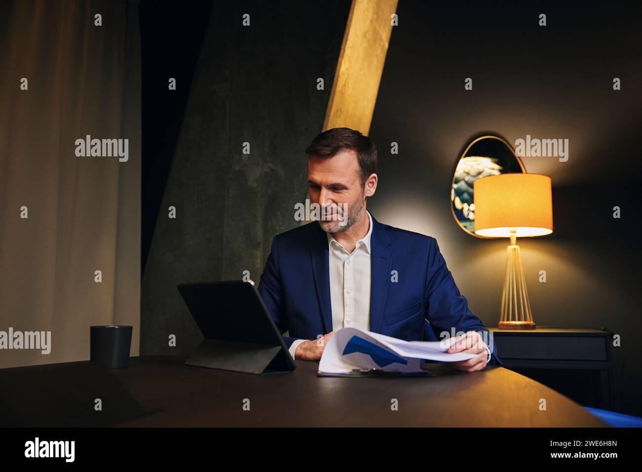 Smiling mature businessman analyzing data and using tablet PC in conference room Stock Photo