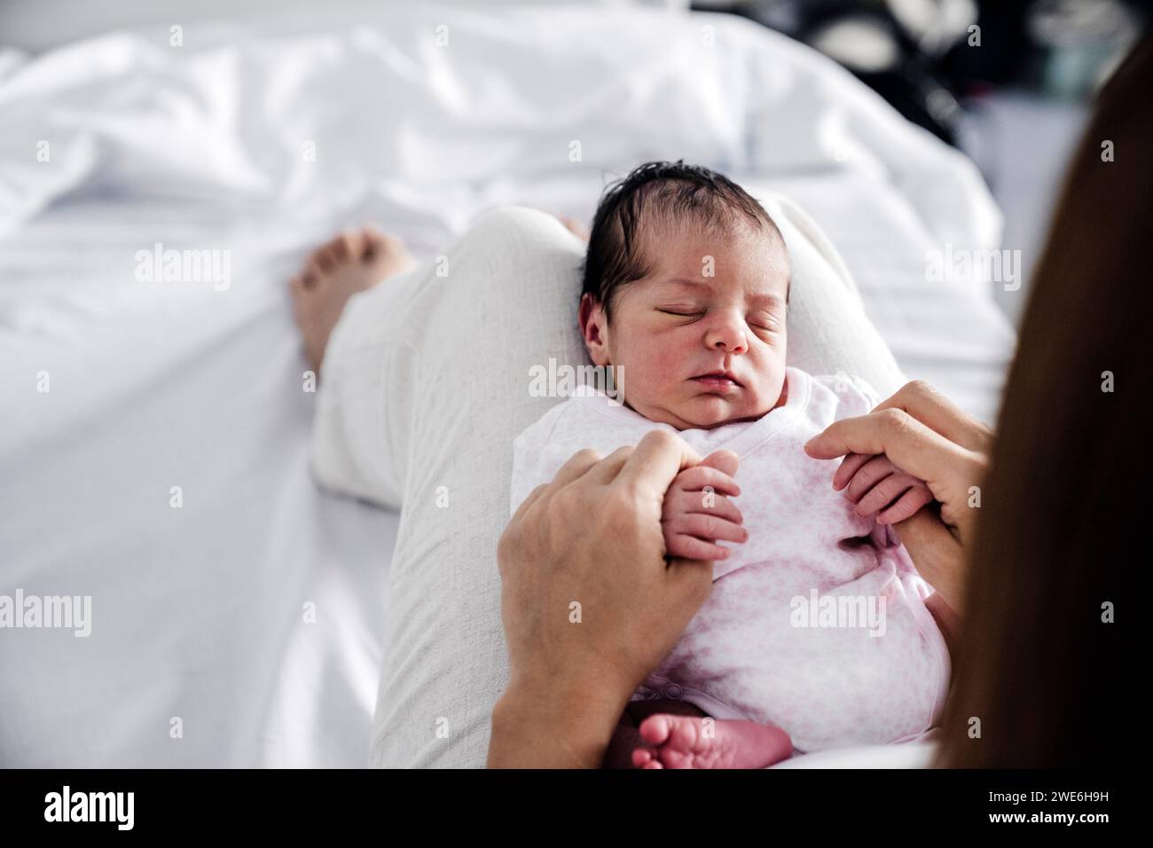 Baby girl sleeping on mother's lap in hospital Stock Photo