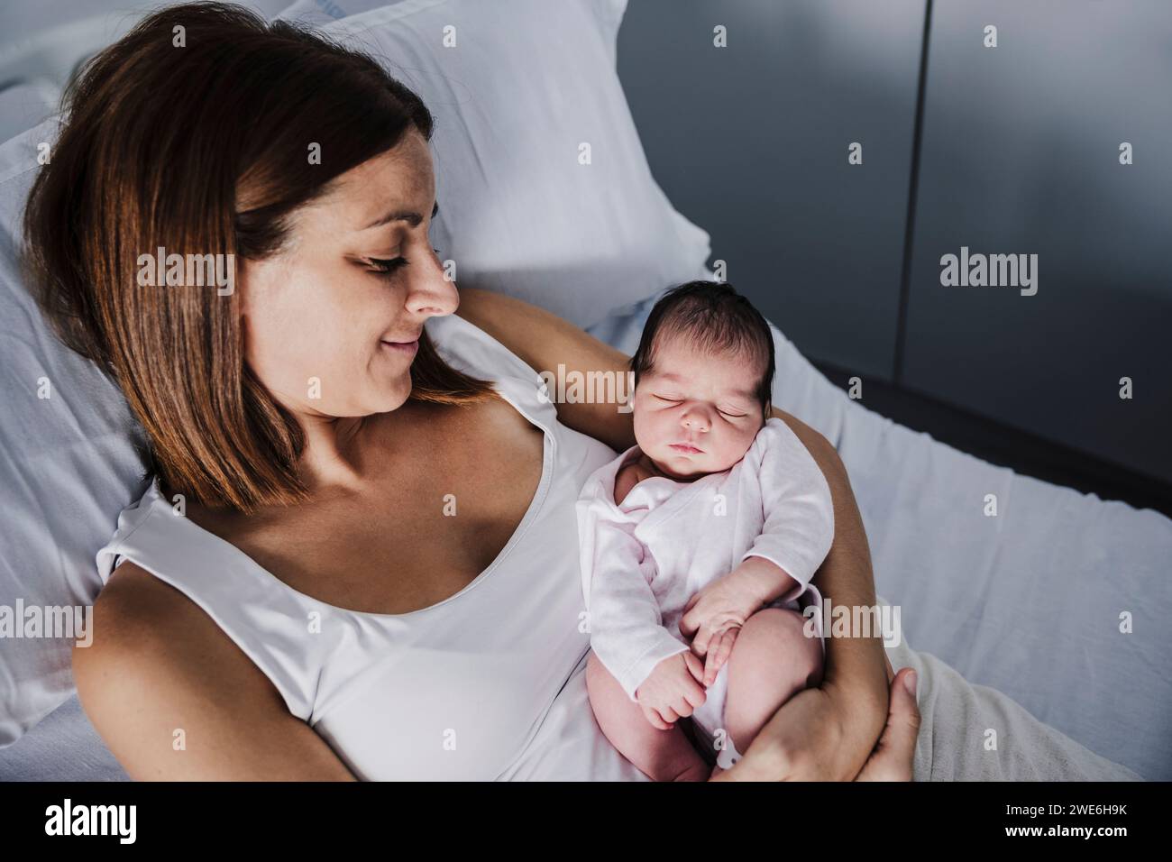Baby girl sleeping in mother's arms at hospital Stock Photo