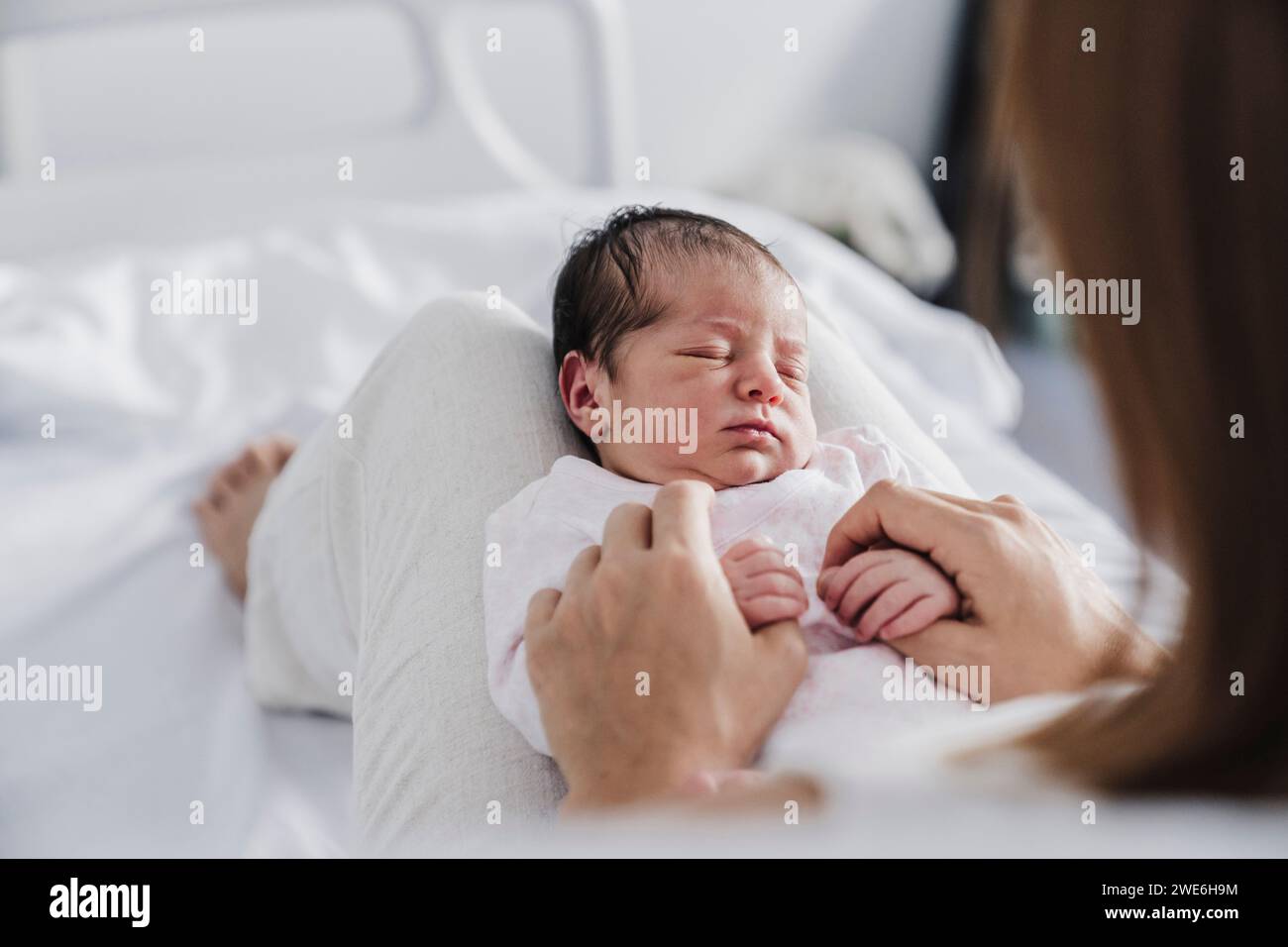 Cute baby girl sleeping on mother's lap in hospital Stock Photo
