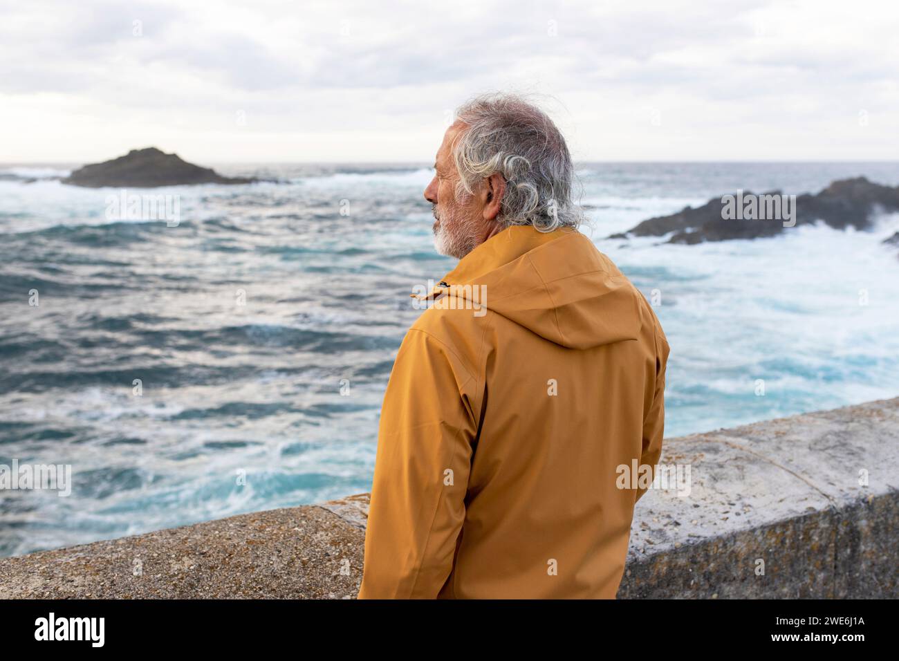 Thoughtful senior man wearing jacket and looking at sea Stock Photo