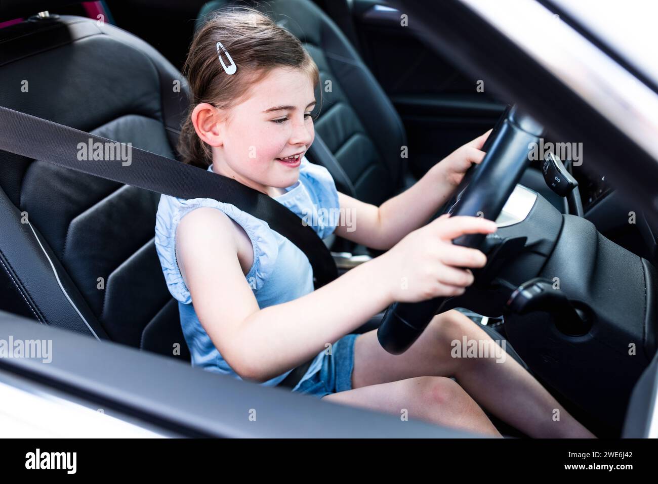Excited girl holding steering wheel sitting in car Stock Photo