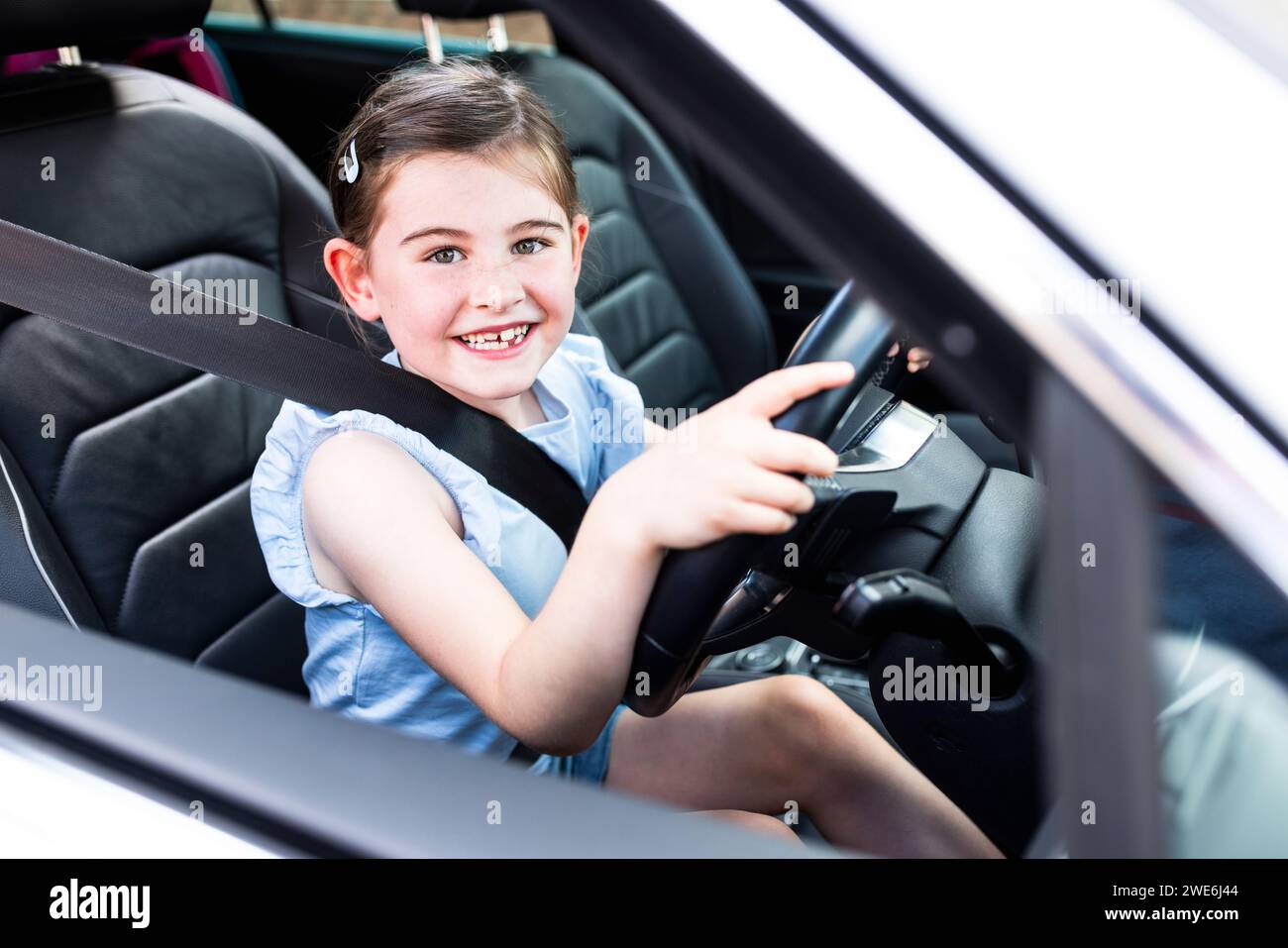 Happy girl holding steering wheel sitting in car Stock Photo