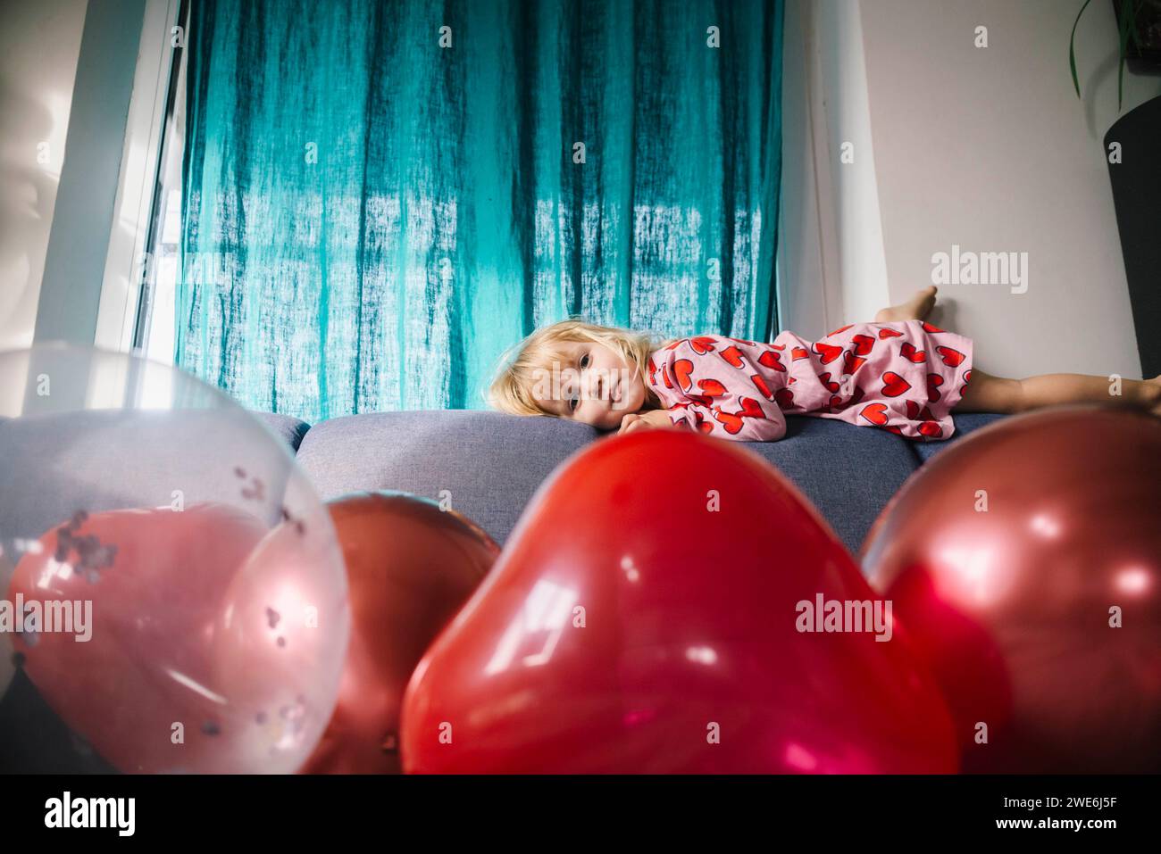 Sad girl lying on sofa with balloons at home Stock Photo - Alamy
