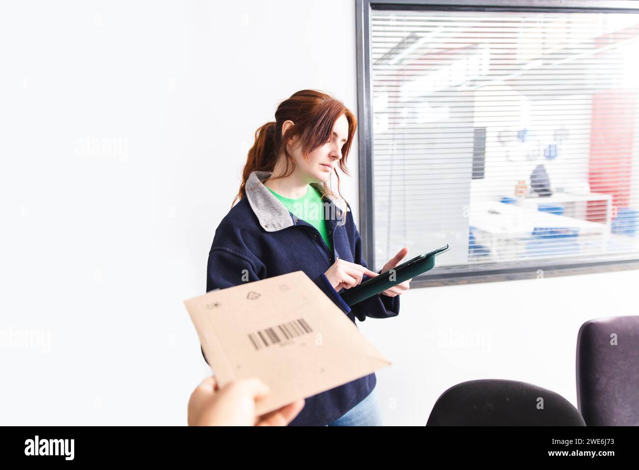 Delivery woman using tablet PC with customer holding package Stock Photo