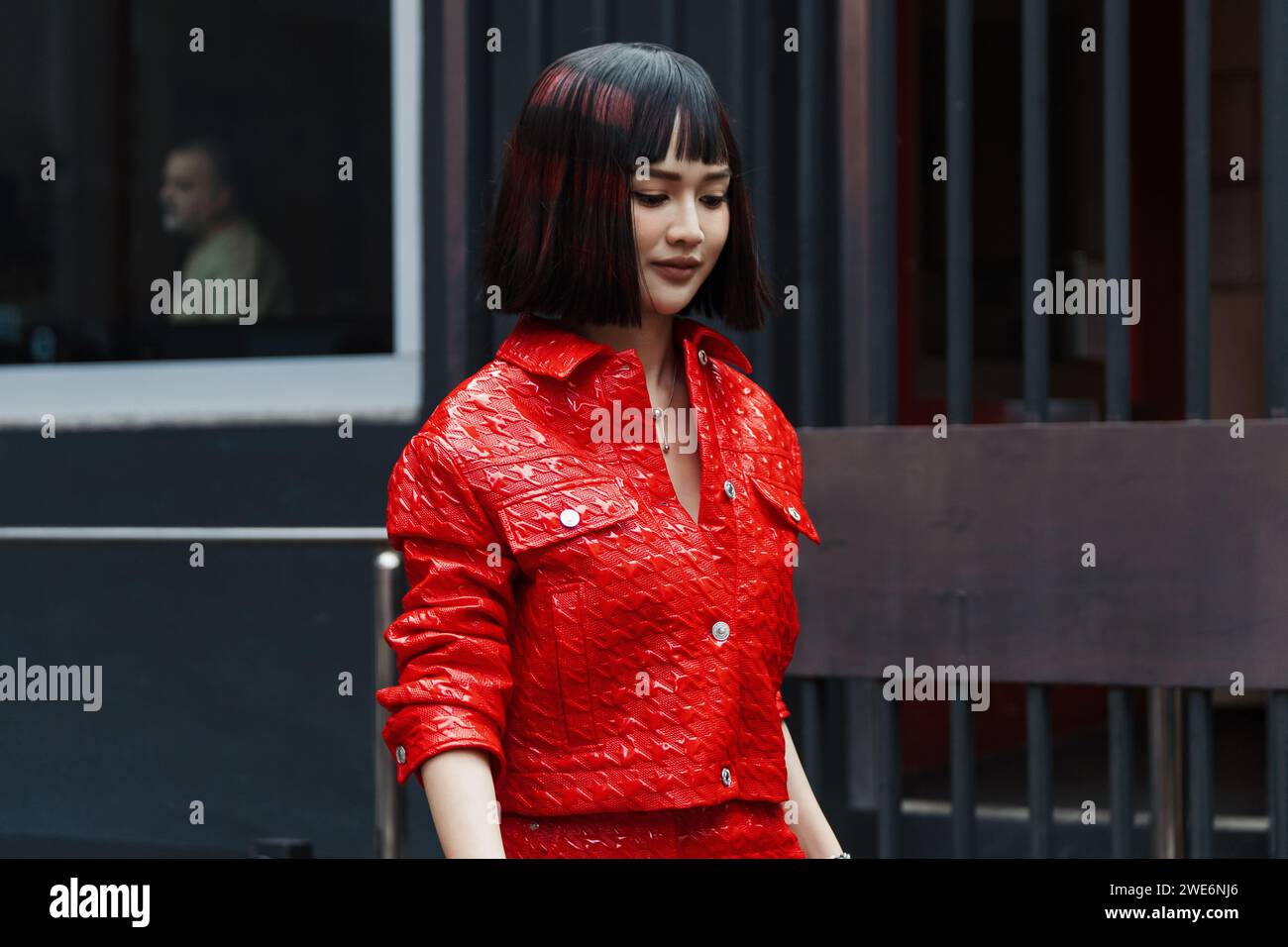 A guest wears a red vinyl MSGM cropped jacket and skirt, outside MSGM show during Milan Fashion Week Womenswear Spring/Summer 2024. Stock Photo