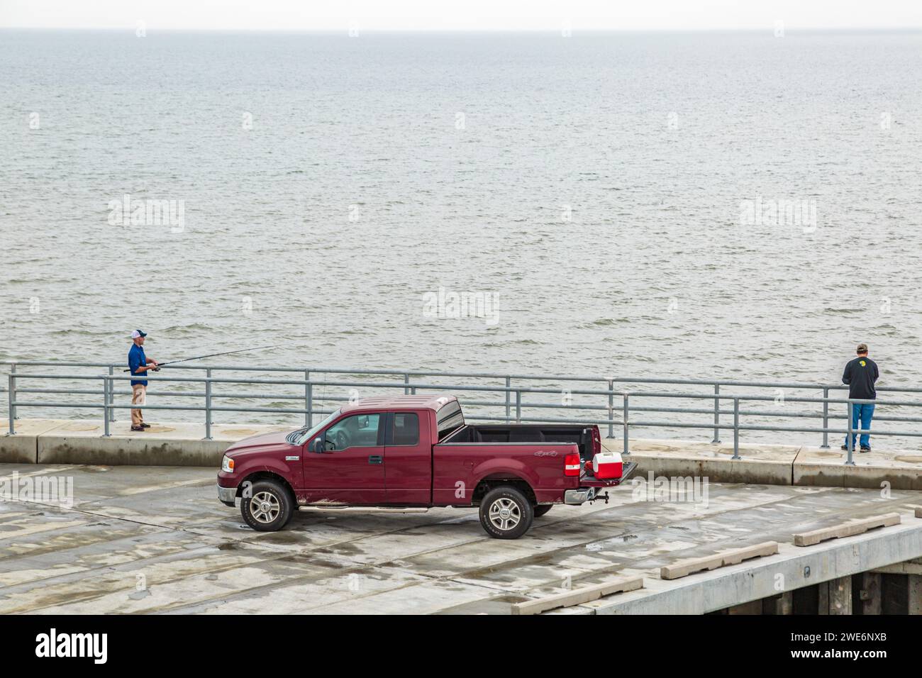 Men fishing from fishing pier next to a red Ford F150 pickup truck in
