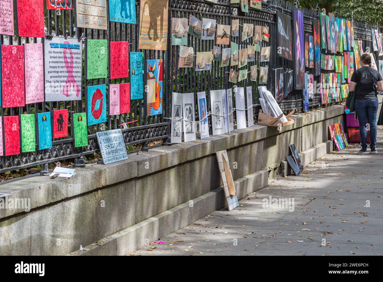 Art pieces hanging on wrought iron fence around Jaskson Square in the