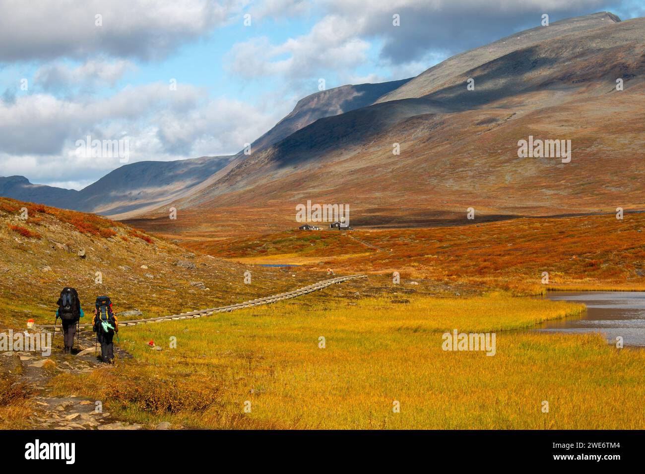Two hikers walking toward Salka Mountain Hut on Kungsleden trail, Lapland, Sweden Stock Photo