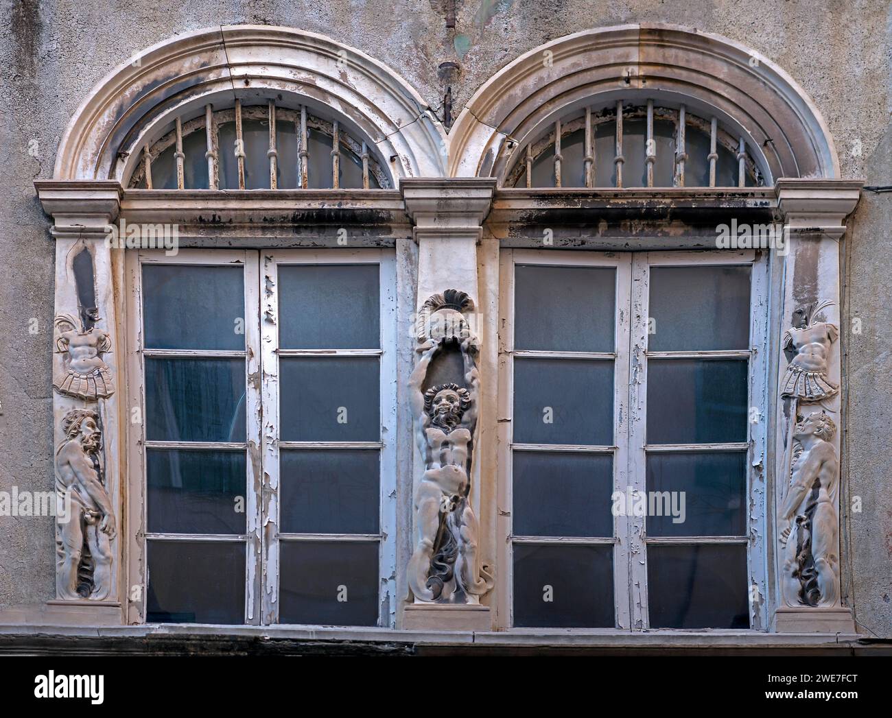 Historic arched windows framed with Roman relief motifs, old town centre in Genoa, Italy Stock Photo