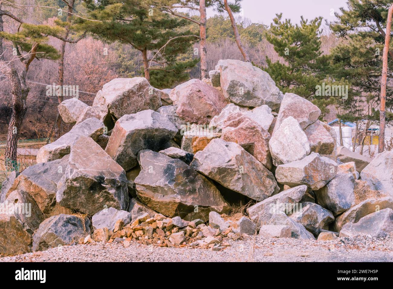 Closeup of large pile of boulders in countryside with evergreen trees in background in South Korea Stock Photo