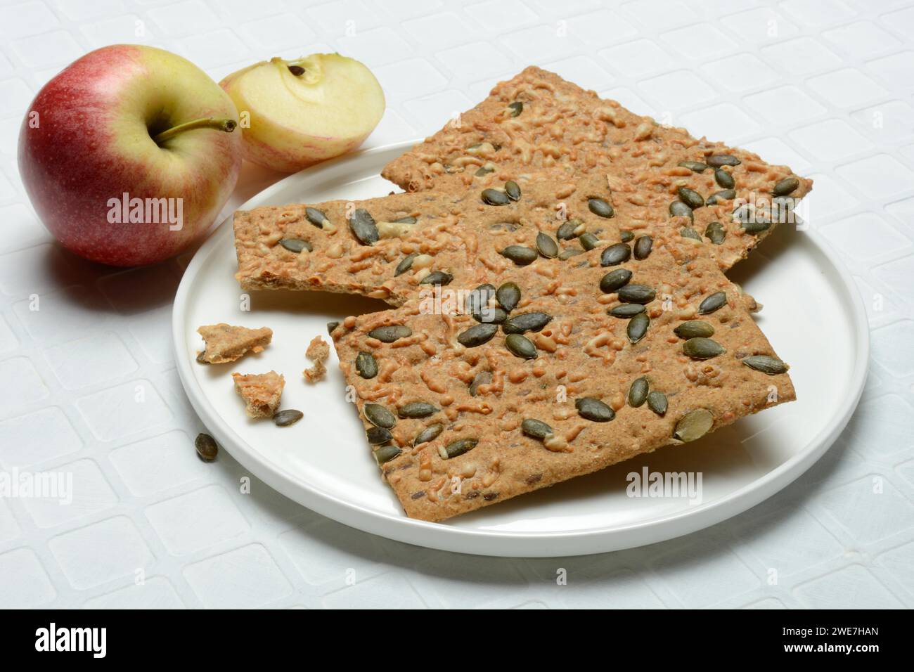 Crispbread with seeds on a plate and apple Stock Photo