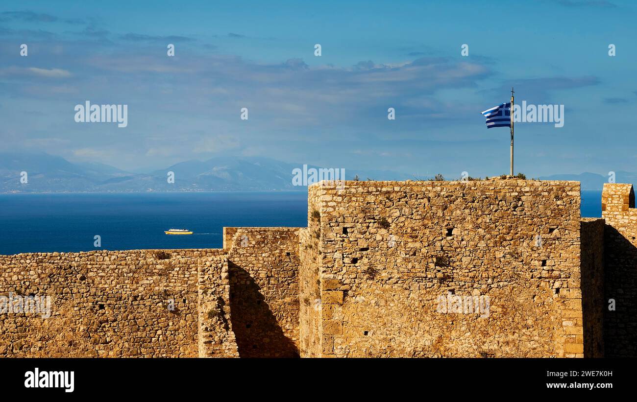 Historic fortress walls under a partly cloudy sky with Greek flag and ...