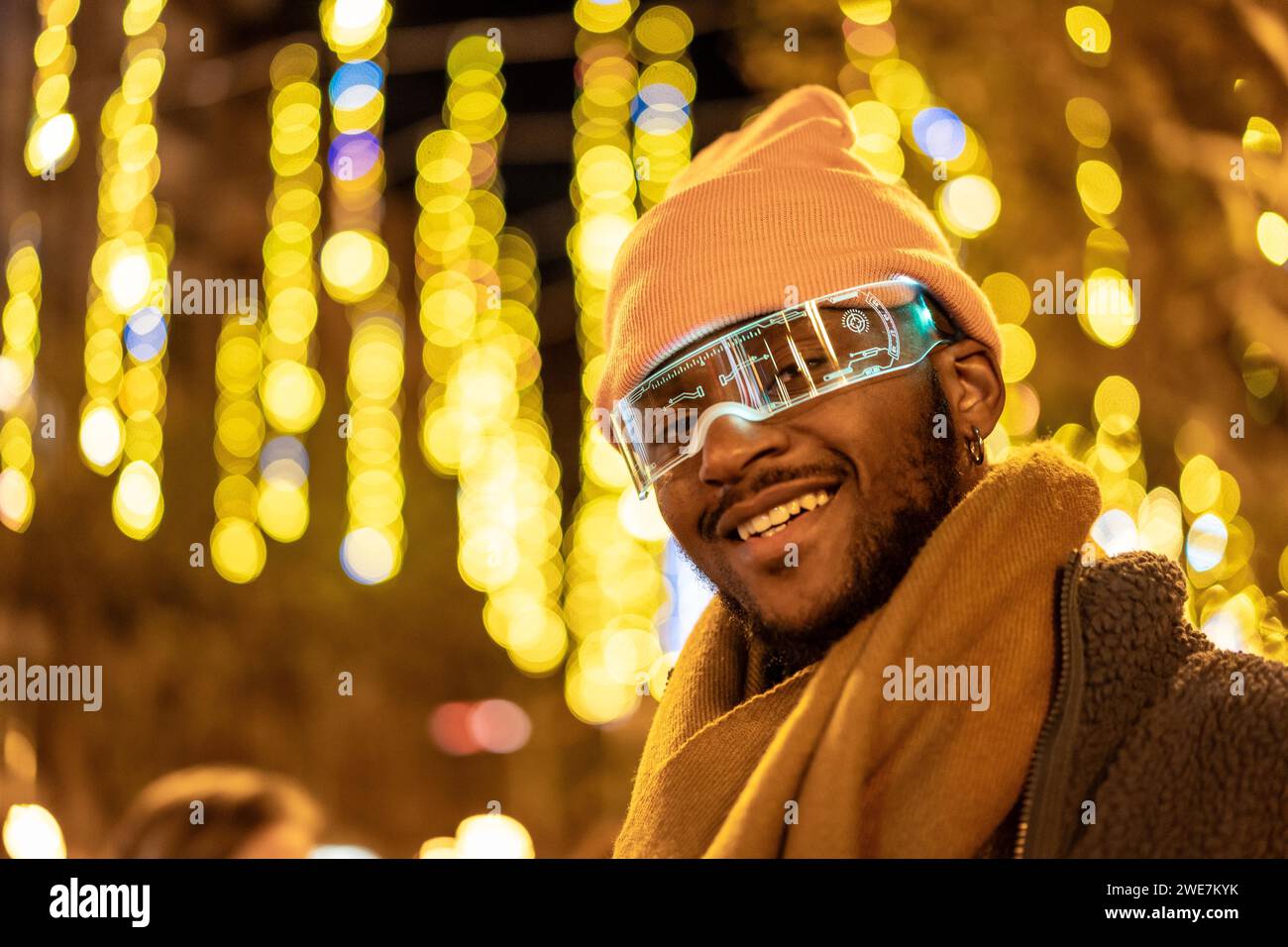 Cool african man wearing smart glasses in the city at night with lights decorating the streets Stock Photo