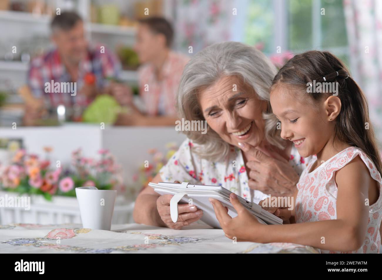 Cute little girl with her grandmother looking at tablet Stock Photo - Alamy