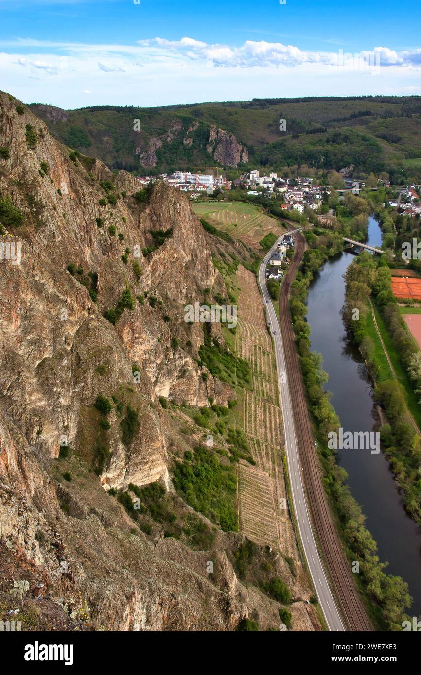 Bad Munster, Germany - May 9, 2021: Vineyard at the bottom of a cliff at Rotenfels next to a road along the Nahe River on a spring day in Bad Munster, Stock Photo