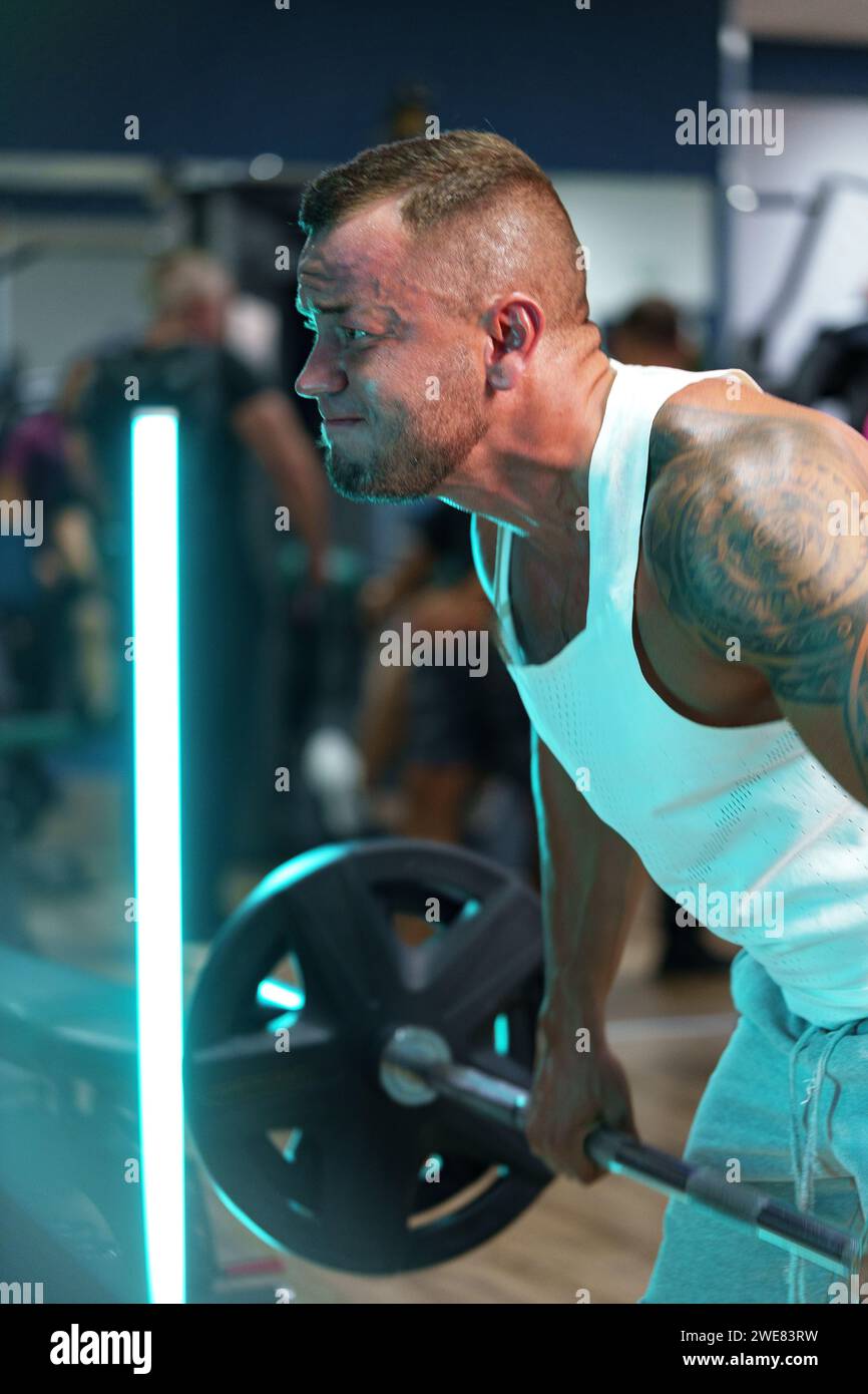 Man bodybuilder in white shirt training in a gym Stock Photo