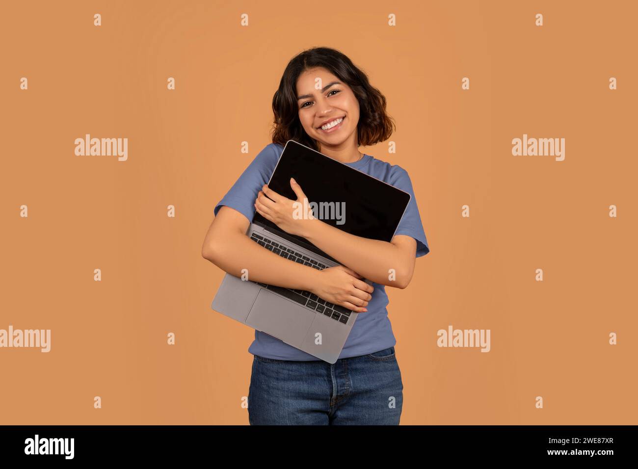 Overjoyed young middle eastern woman hugging her laptop Stock Photo
