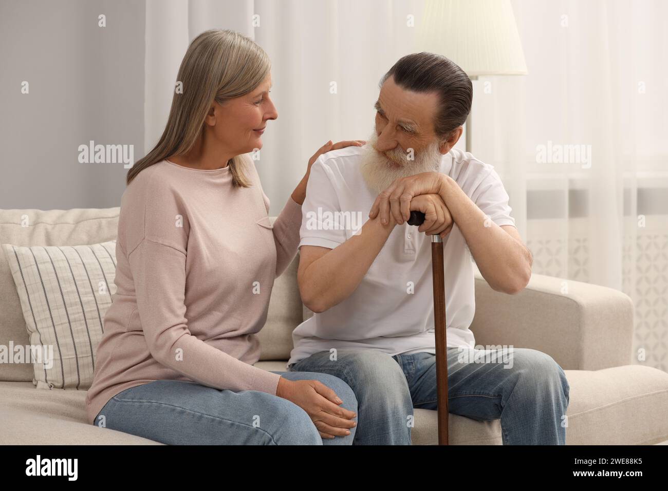 Senior man with walking cane and mature woman on sofa at home Stock ...
