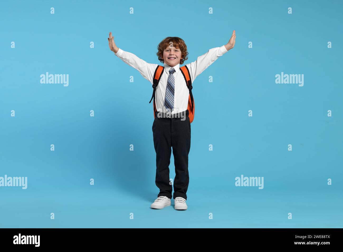 Happy schoolboy with backpack on light blue background Stock Photo - Alamy