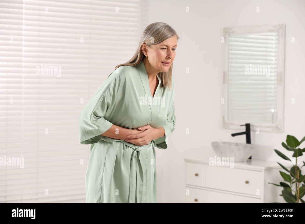Menopause. Woman suffering from digestive problems in bathroom Stock Photo Alamy