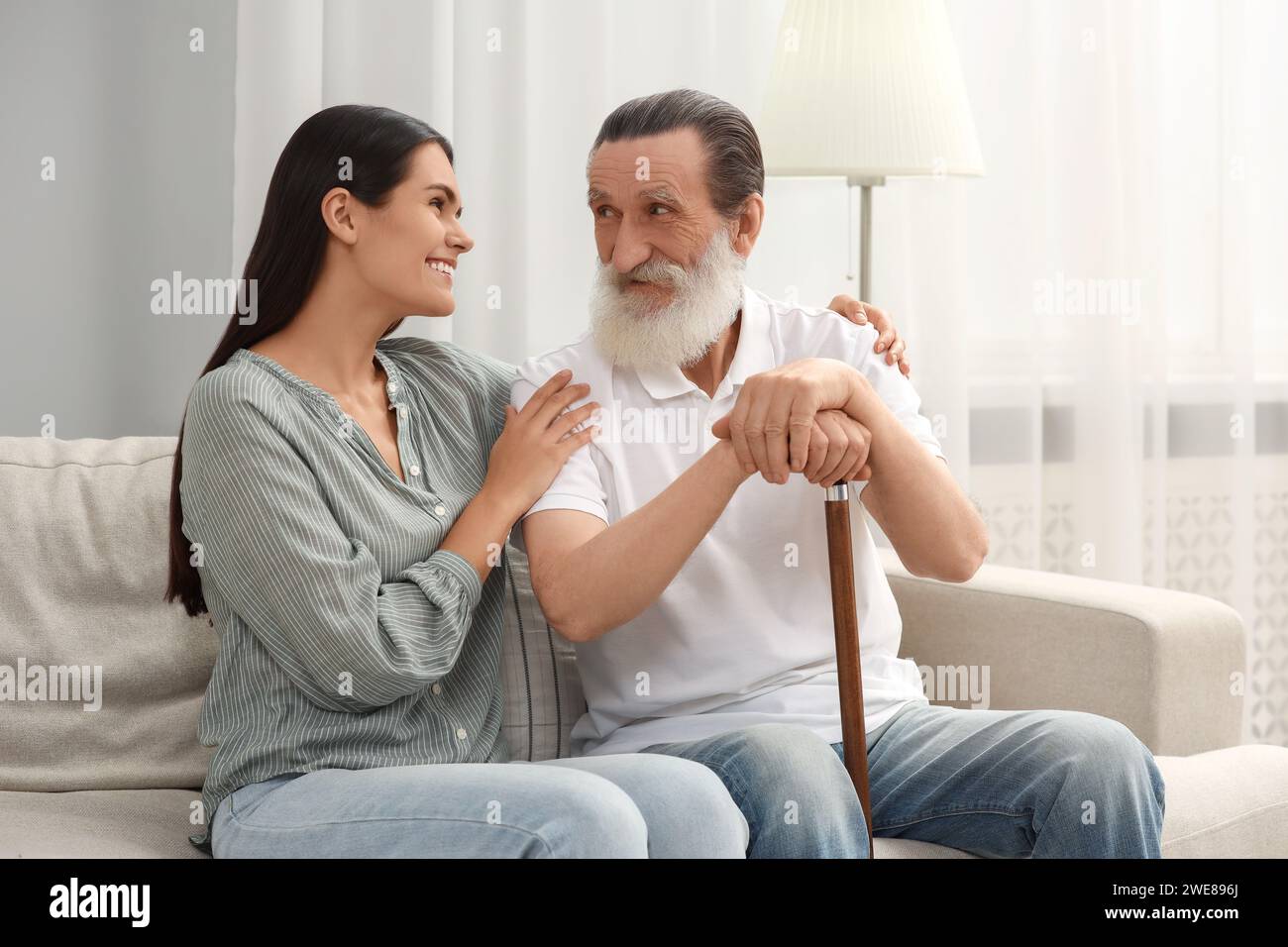 Senior man with walking cane and young woman on sofa at home Stock ...