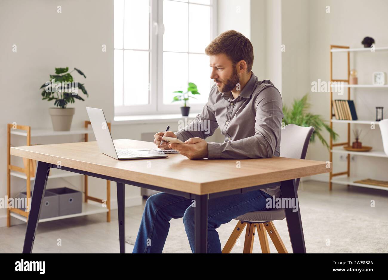 Focused businessman using smartphone and laptop computer at home office Stock Photo