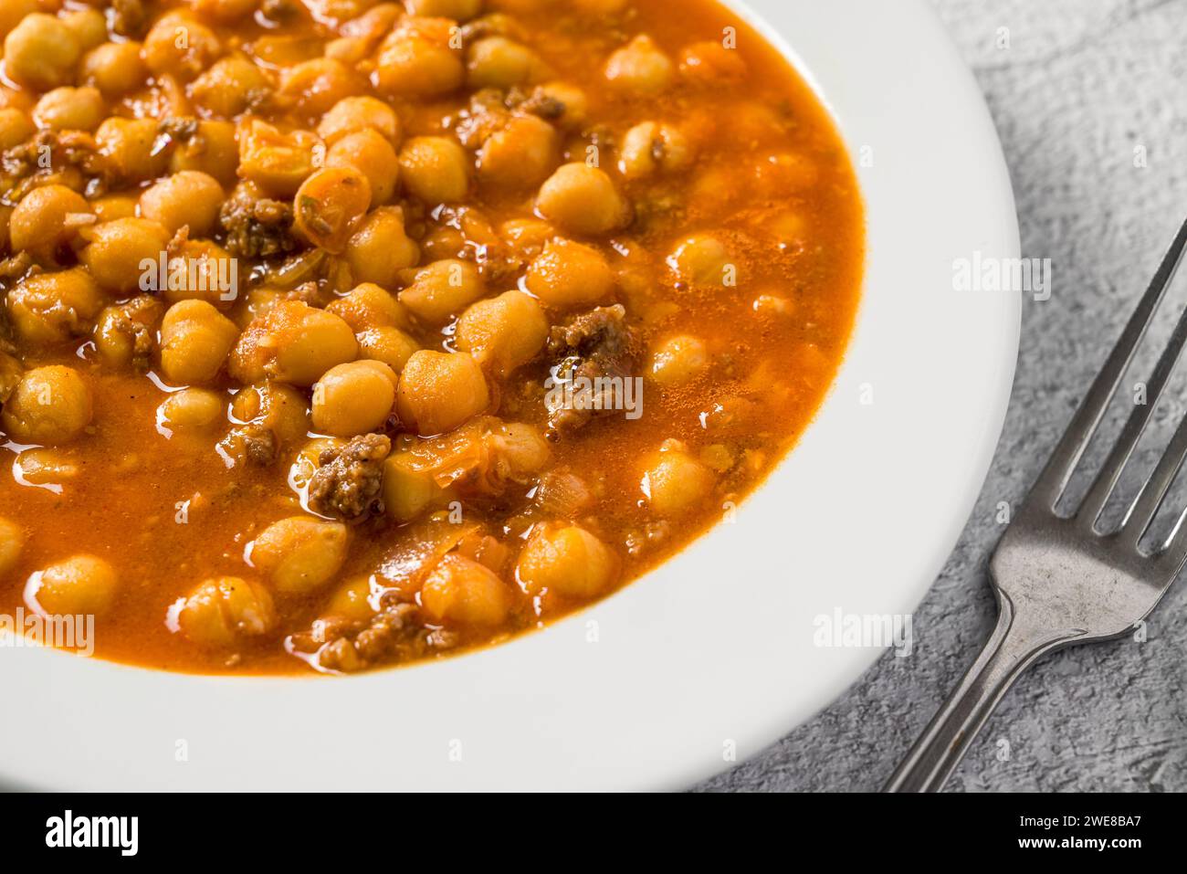 Chickpea stew with minced meat on a white porcelain plate on a stone table Stock Photo