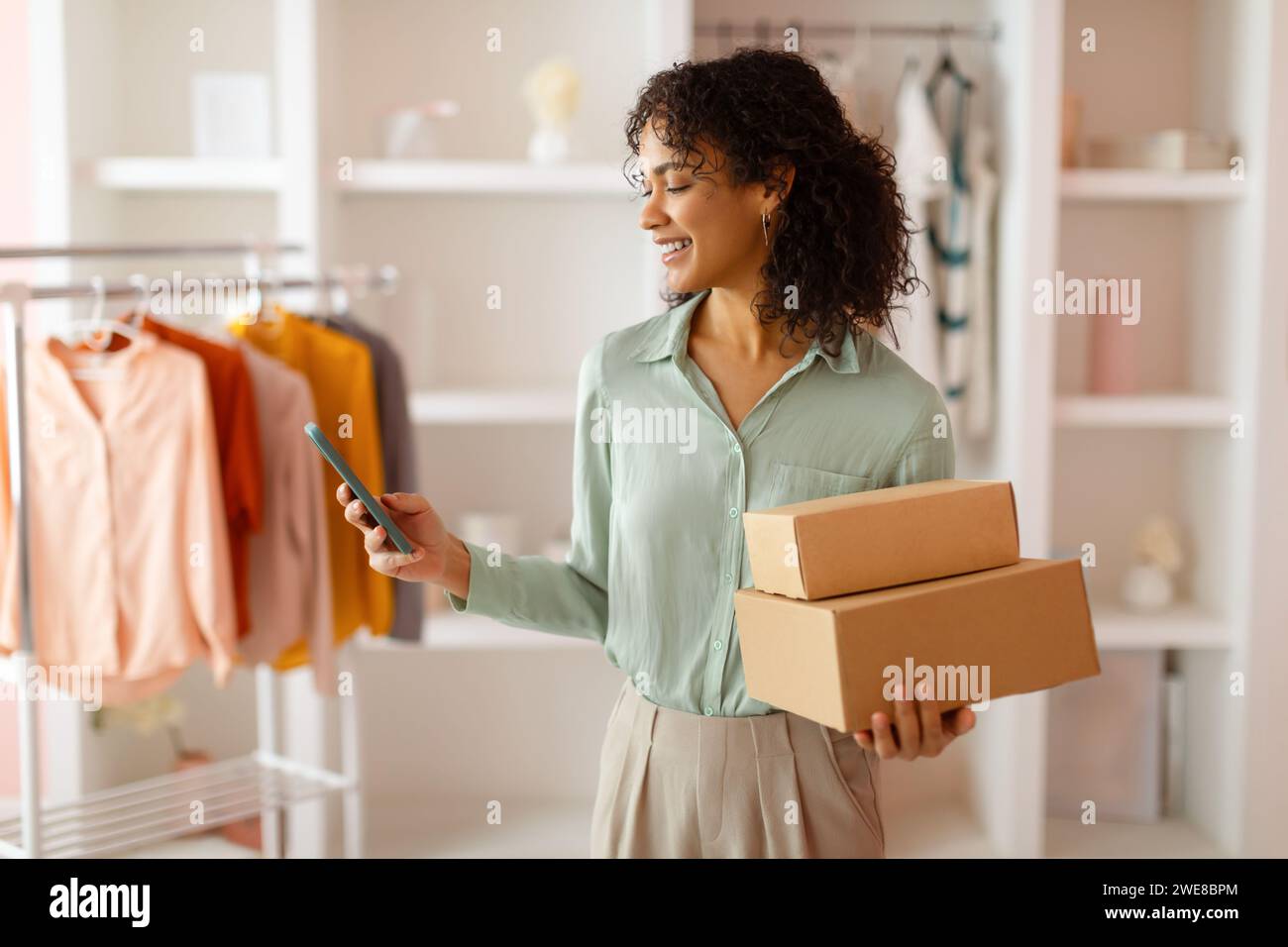 Designer with packages using smartphone in studio Stock Photo
