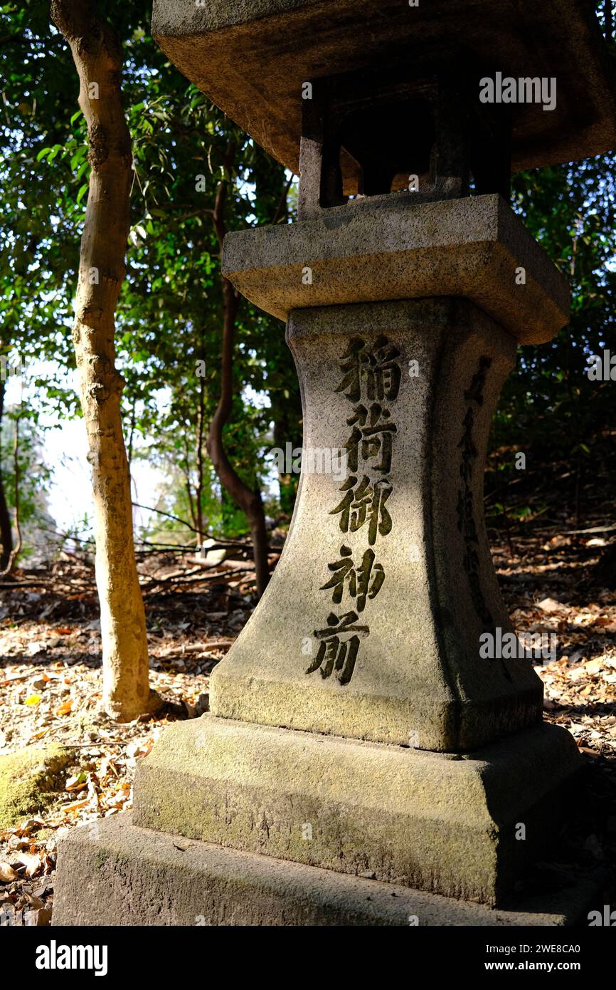 A traditional Japanese stone lantern, inscribed with kanji, standing
