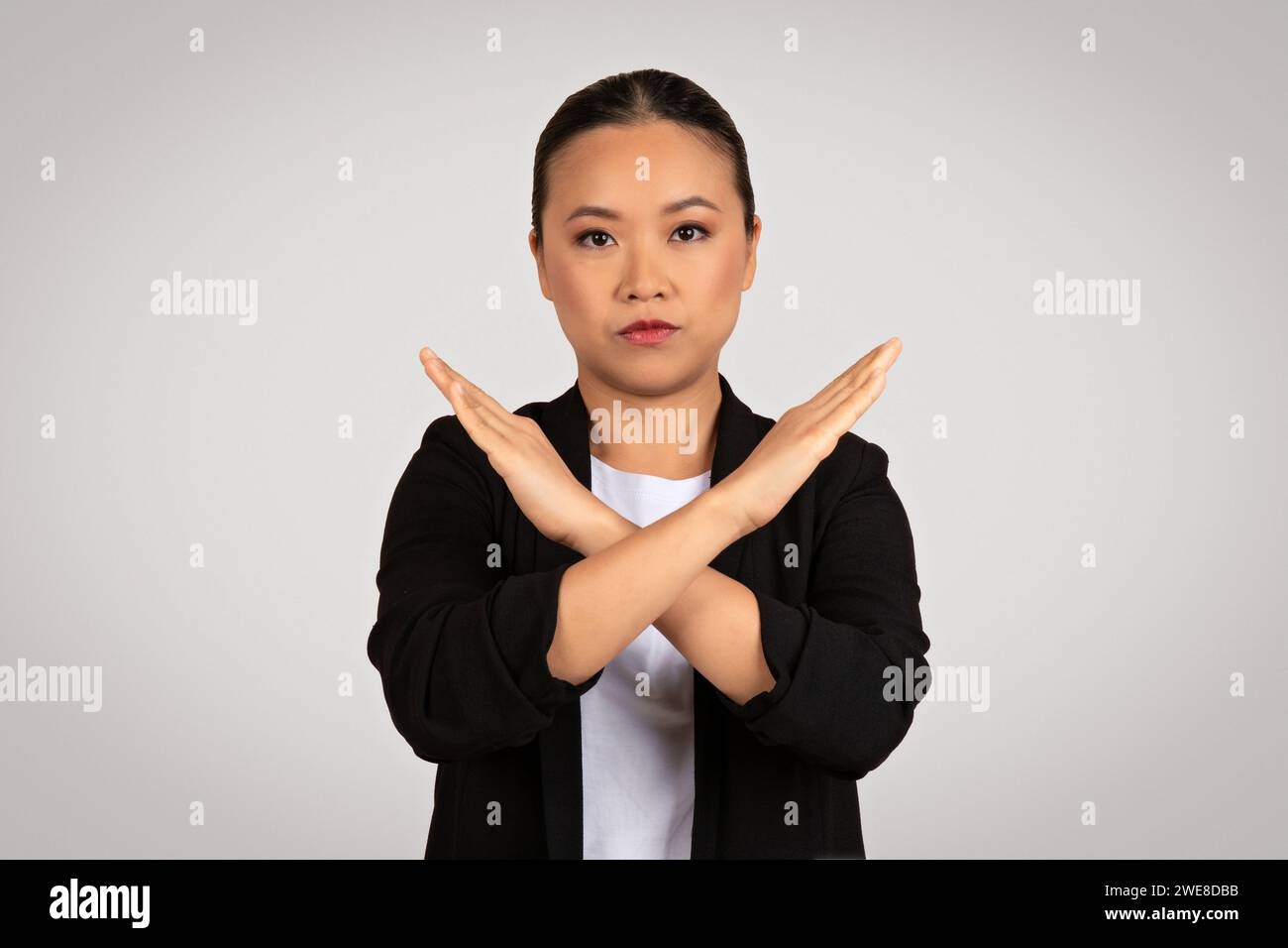 Assertive Asian businesswoman in a black suit making a strong 'no ...