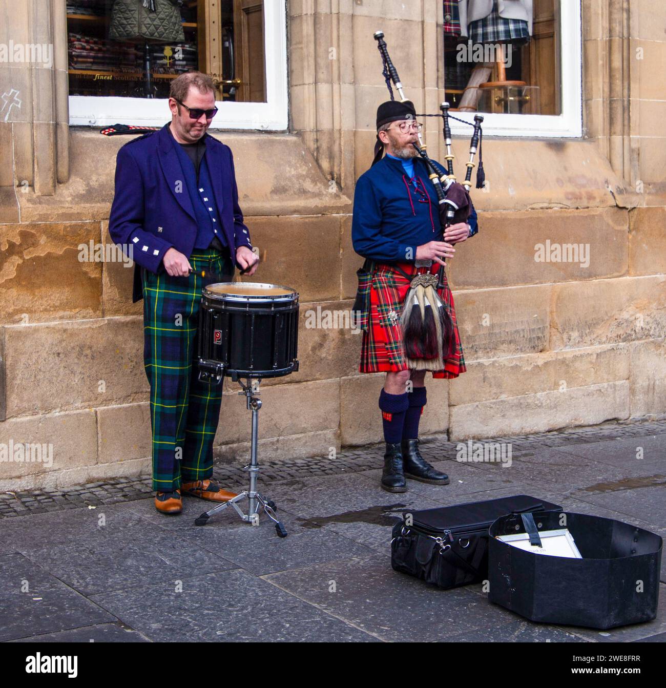 Street musicians performing, one playing the bagpipes and the other playing a snare drum in an urban setting Royal Mile Edinburgh. Stock Photo
