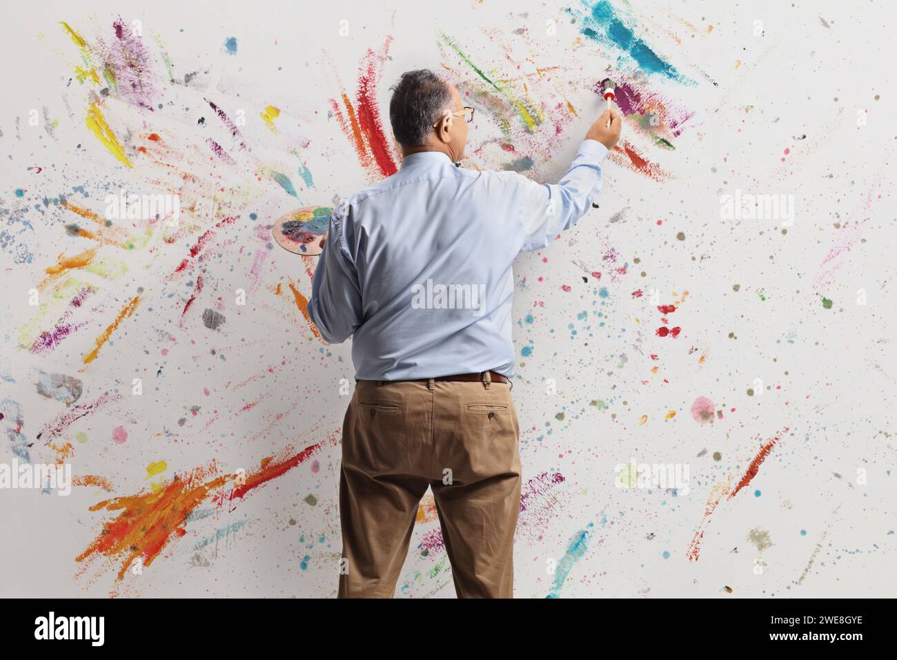 Rear view shot of a mature man painting with acyrlic paints on a wall Stock Photo