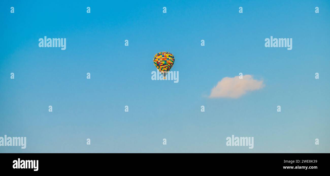 Panoramic shot of a multicoloured hot air balloon seen against a blue sky Stock Photo