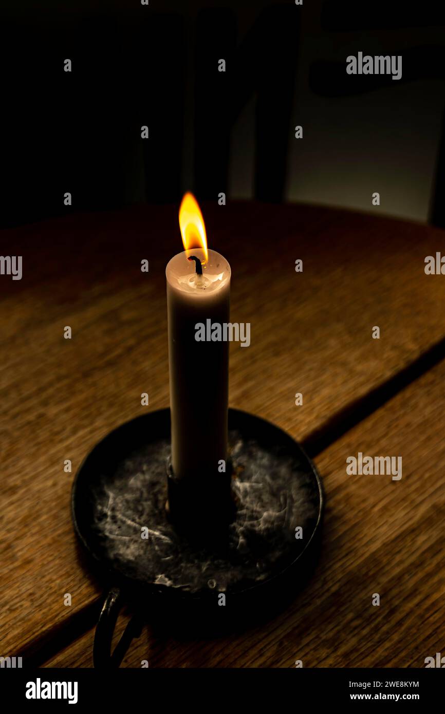 High angle of burning and illuminating wax candle in handle tray while