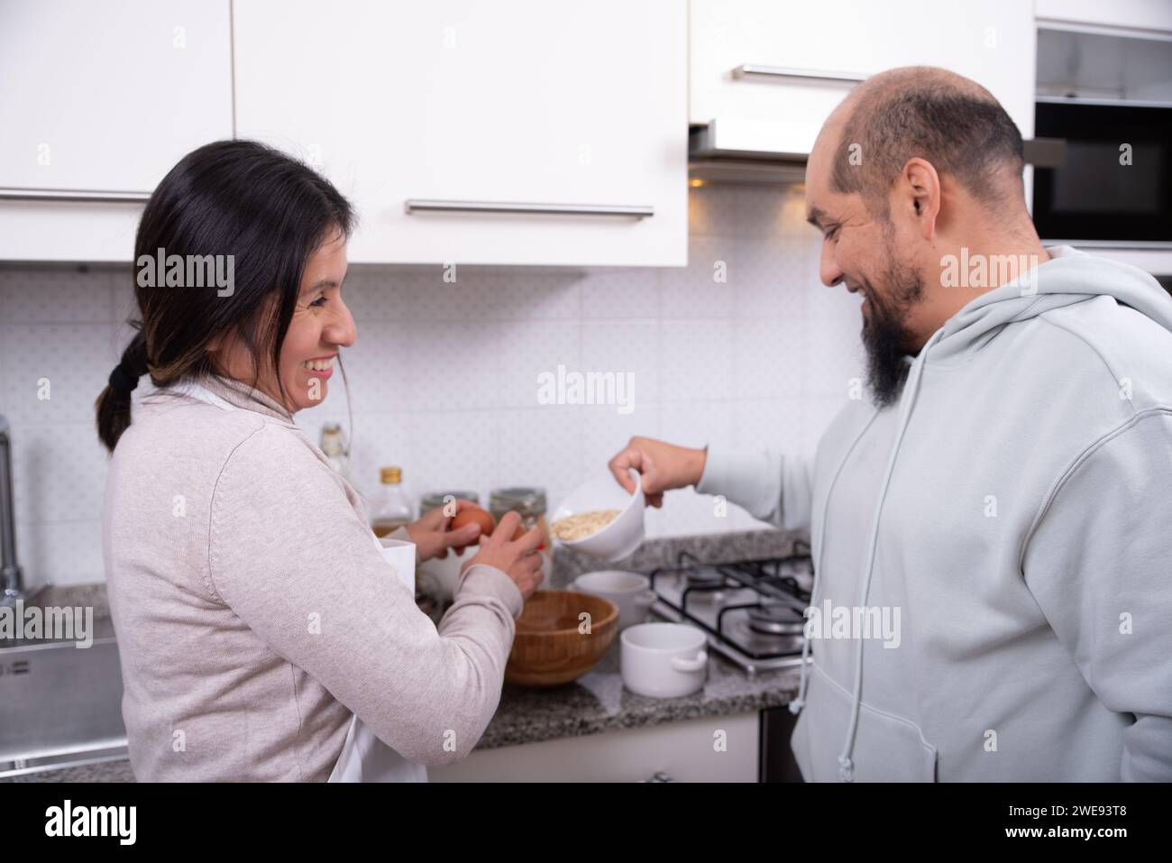 Couple talks and has fun while preparing cookies at home. Stock Photo