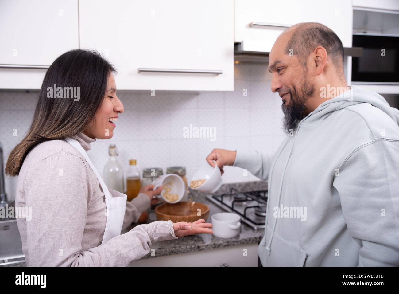 Couple talks and has fun while preparing cookies at home. Stock Photo