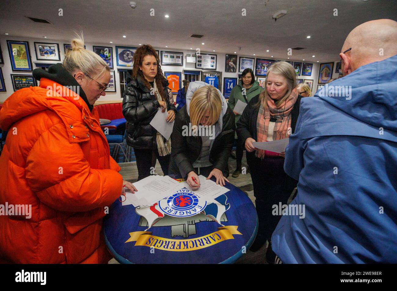 Community worker and activist Jamie Lee Mogey (left) at Carrickfergus Glasgow Rangers Supporters Club, collecting signed letters from members of the unionist and loyalist community calling upon elected representatives to keep their word and remain outside of Stormont until the Irish Sea Border has been removed. Picture date: Tuesday January 23, 2024. Stock Photo