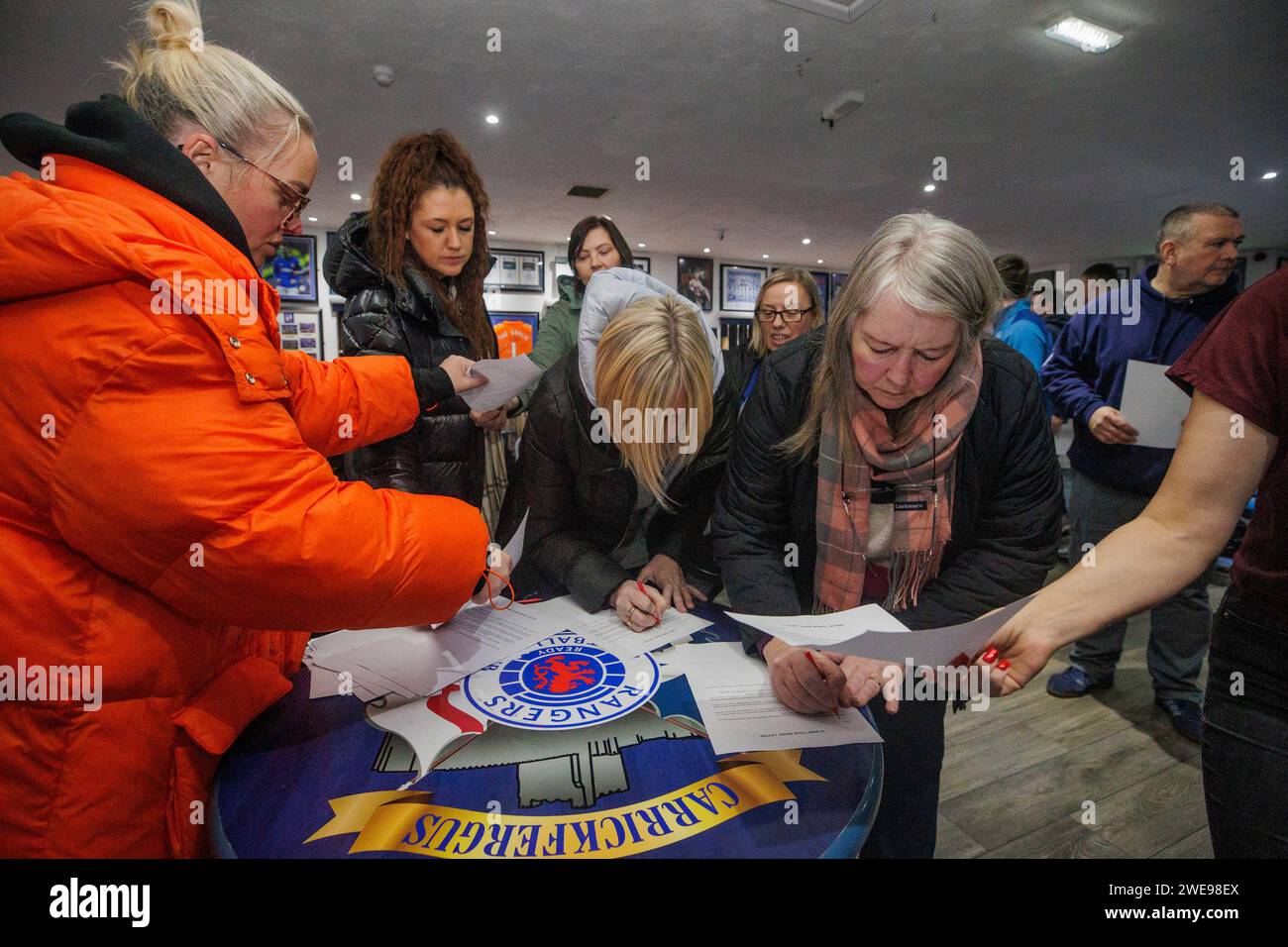 Community worker and activist Jamie Lee Mogey (left) at Carrickfergus Glasgow Rangers Supporters Club, collecting signed letters from members of the unionist and loyalist community calling upon elected representatives to keep their word and remain outside of Stormont until the Irish Sea Border has been removed. Picture date: Tuesday January 23, 2024. Stock Photo