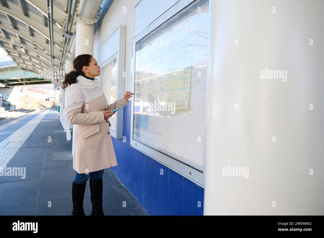 Full length side view of female traveler standing at a board with train ...