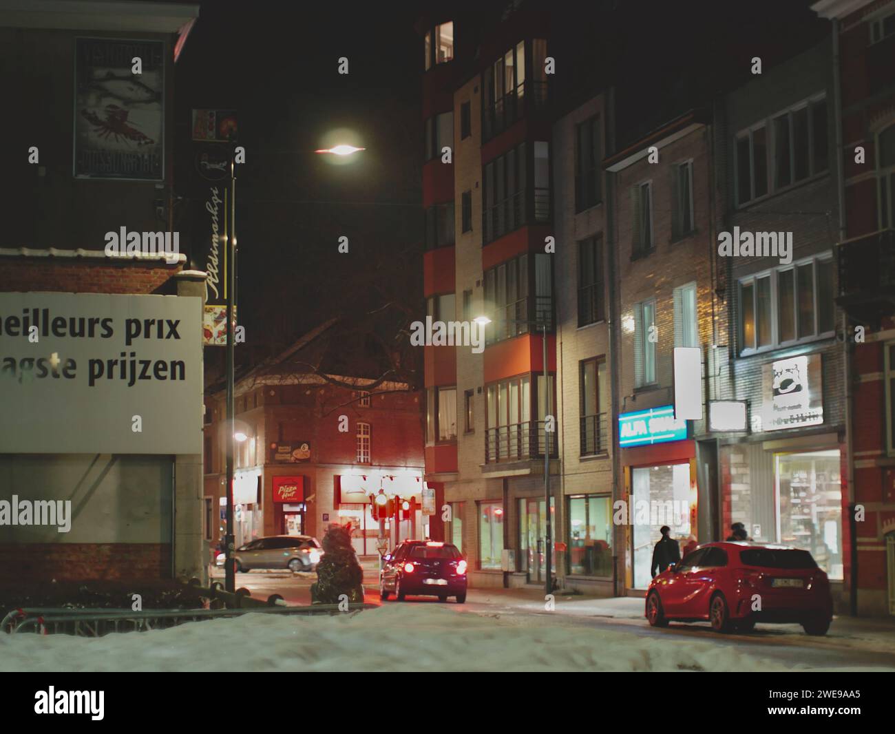 Brussels, Belgium January 20, 2024. Landscape of night winter snow-covered Brussels. The frame captured the Colruyt Group sign, Pizza Hut llogo Stock Photo