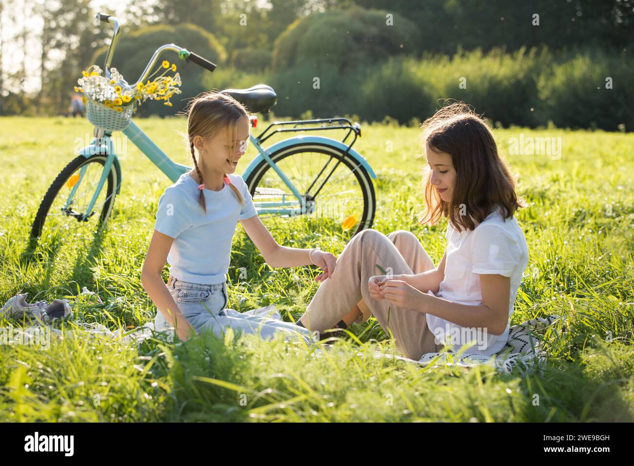 Two girls enjoy summer and vacations together spending time on green grass lawn in park, Stock Photo