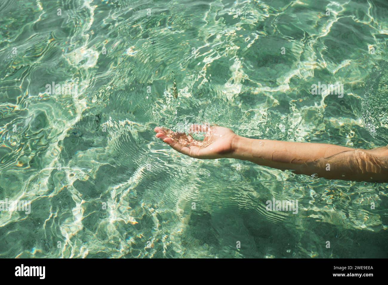 Hands with pure water. Closeup of a woman's hand touching the lake water. A person's hand reaching out to touch a rippling water surface, exploring th Stock Photo