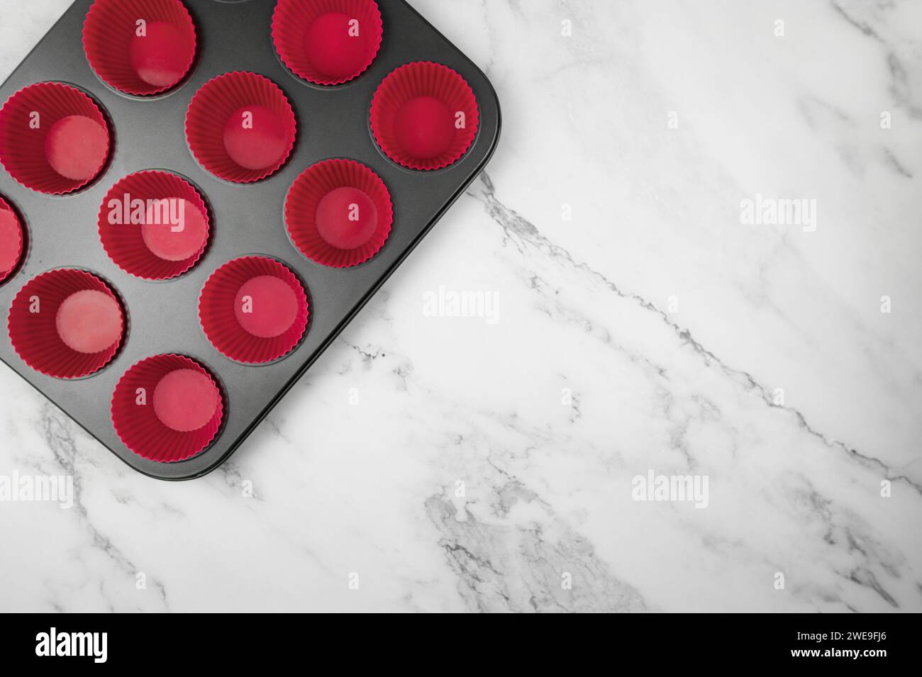 Top view of cupcake pan and silicone cases on white marble background. Muffins and cupcakes cooking, flat lay, copy space. Stock Photo