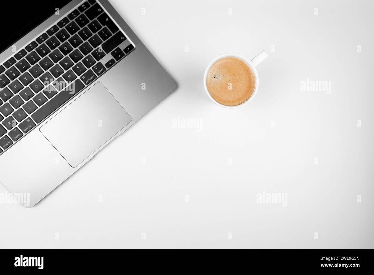 Top view of grey laptop computer on white background. Coffee cup, flat lay, copy space. Stock Photo