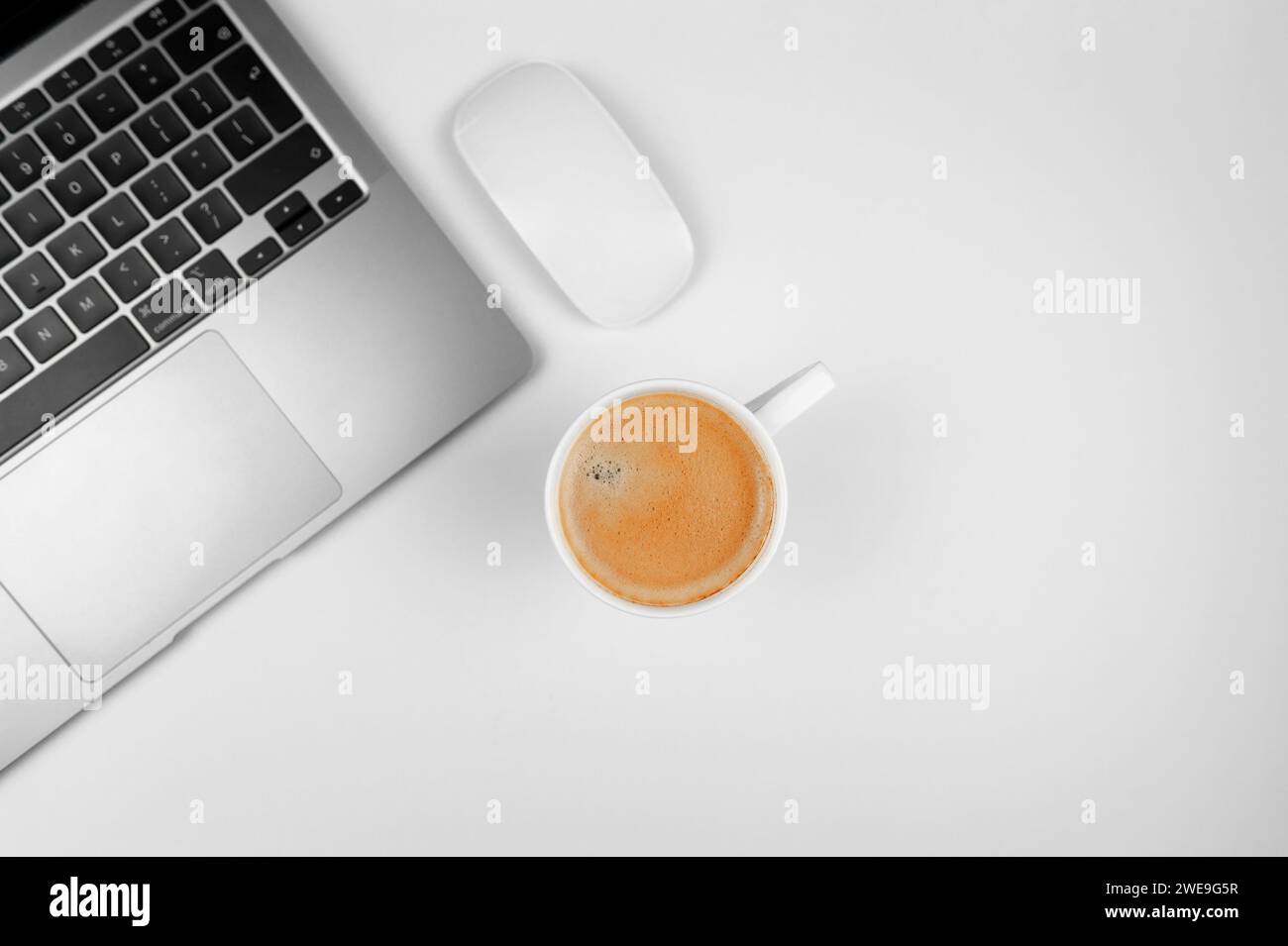 Top view of grey laptop computer on white background. Coffee cup, white mouse, flat lay, copy space. Stock Photo