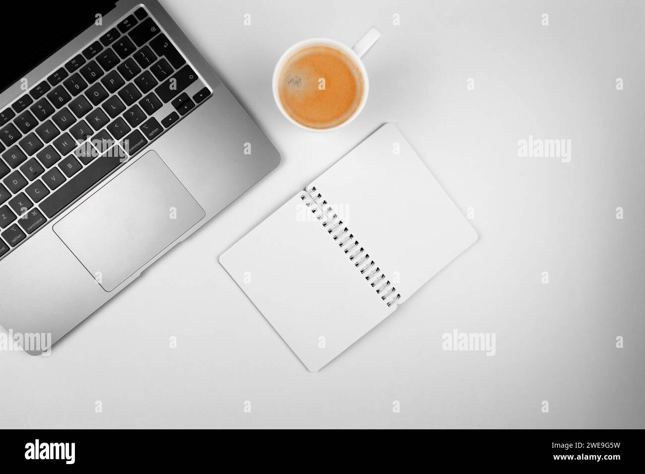 Top view of grey laptop computer on white background. Notebook and coffee cup flat lay, copy space. Stock Photo